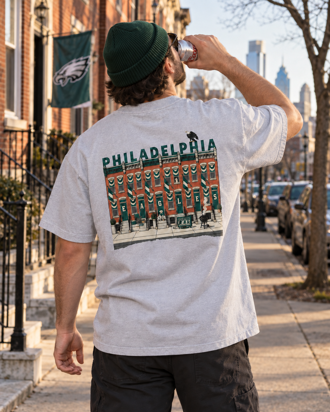 Man in a gray Birds on the Block tee chugging a beer in philadelphia