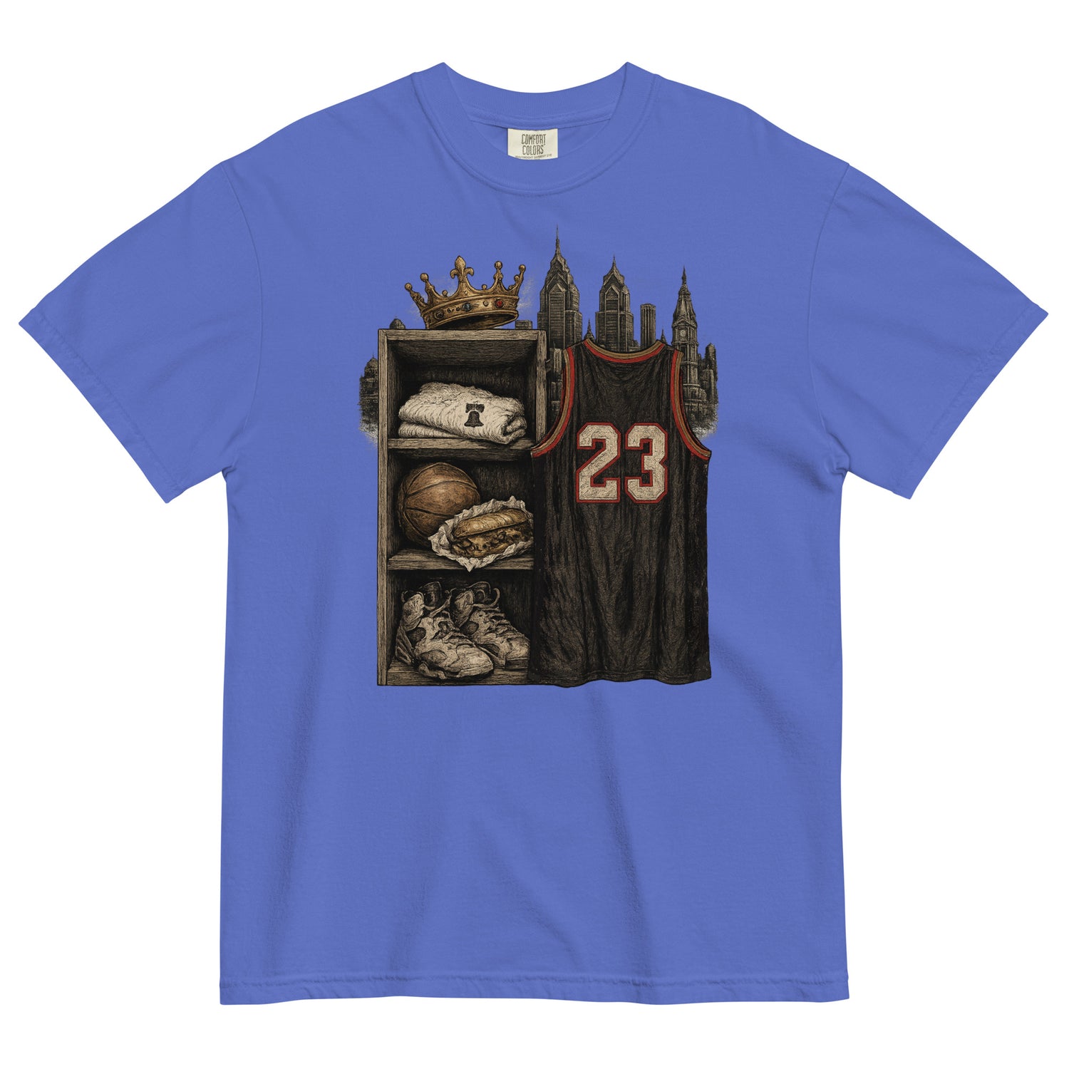 A royal blue short-sleeve t-shirt with a detailed graphic print on the front. The graphic shows a basketball-themed shelf with a crown, a folded sweatshirt, a basketball, sneakers, and a dark basketball jersey with the number 23.